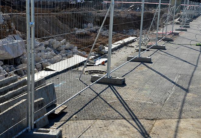 a temporary fence enclosing a construction site with industrial equipment